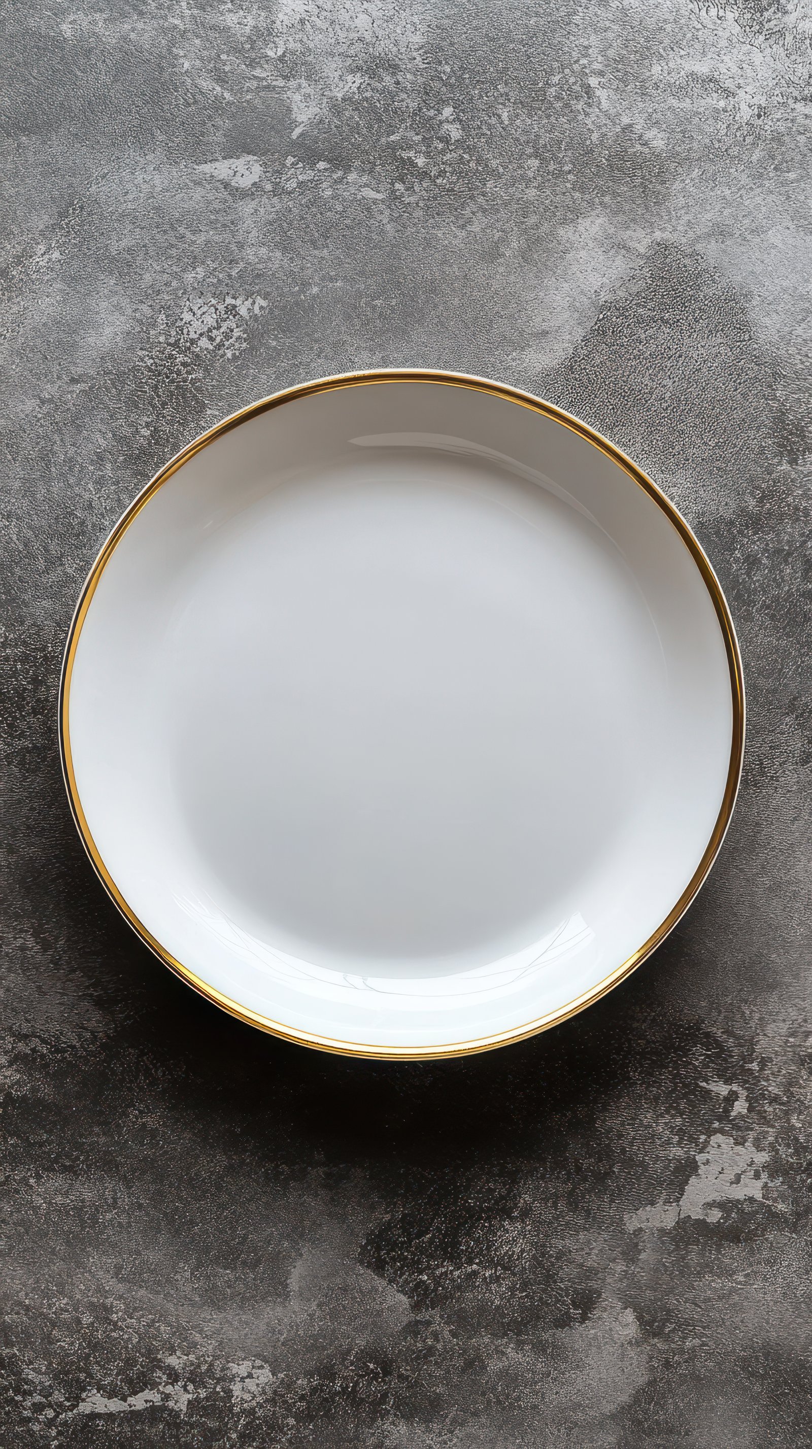 Elegant white plate with golden rim resting on a textured gray surface in a cozy kitchen setting